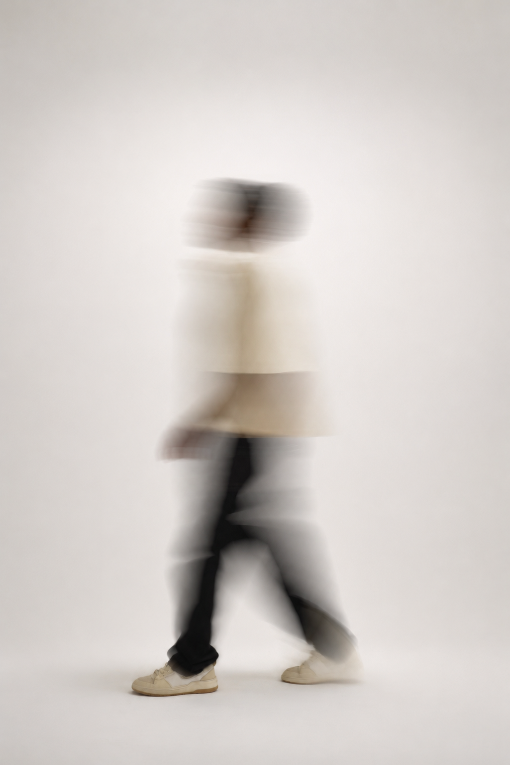 Blurred figure walking in a cream shirt and dark trousers